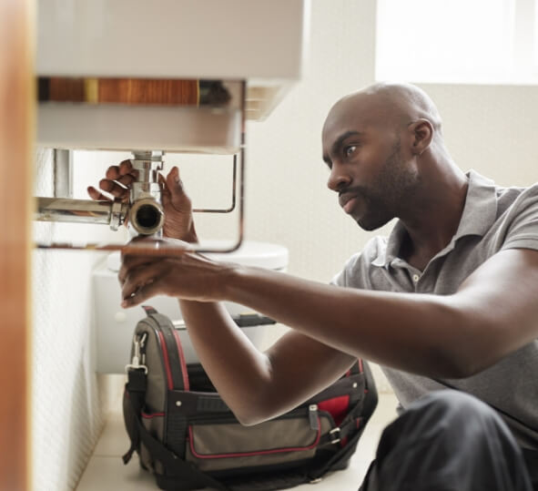 Man adjusting pipe under sink